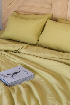 a book is laying on top of a bed with yellow sheets and pillows in front of it