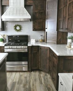 a kitchen with wooden cabinets and white counter tops, stainless steel appliances and wood flooring