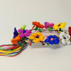 a bunch of different colored flowers on a white table with some colorful bracelets around it