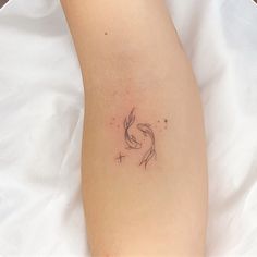 a small tattoo on the leg of a woman's arm, which has a fish in it