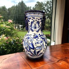 a blue and white vase sitting on top of a wooden table next to a window