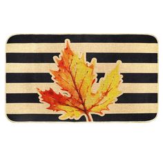 a black and white striped mat with a maple leaf on the front in autumn colors