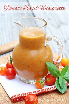 a glass pitcher filled with liquid sitting on top of a cutting board next to tomatoes