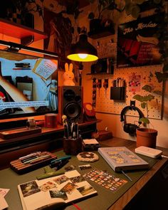 a desk with various items on it in front of a television screen and some books