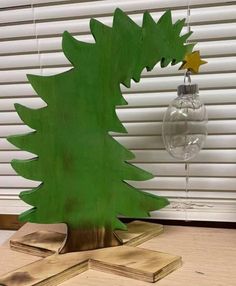 a christmas tree made out of plywood with a glass ornament hanging from it