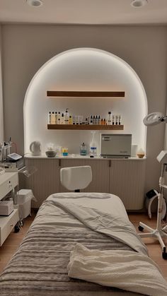 a bed in a room with an arched window and shelves above it that have bottles on the wall