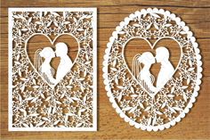 two paper cut out of the shape of a couple kissing in a heart shaped frame