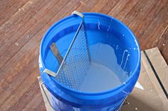 a blue bucket filled with water sitting on top of a wooden floor next to a cardboard box