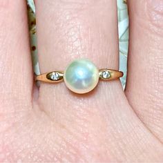 a woman's hand with a pearl and diamond ring on top of her finger