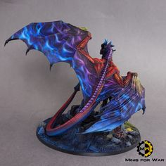 a blue and red dragon statue on a black base with flames coming out of its wings