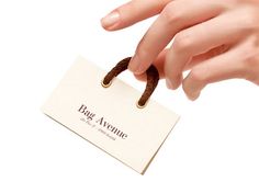 a woman's hand holding a business card with the word b & g avenue on it