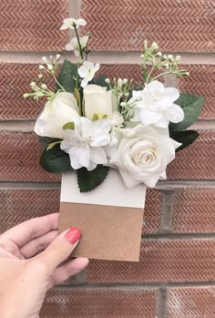 a person holding a small box with flowers in it on the side of a brick wall