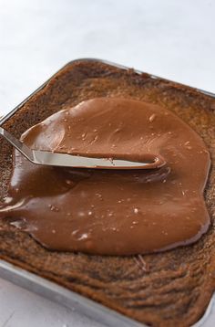 a spoon is sitting on top of a piece of bread with chocolate spread over it