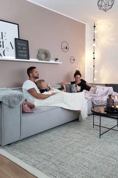 a family is relaxing on the couch in their living room with pink walls and white furniture