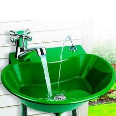 a green sink sitting on top of a metal stand in front of a white house