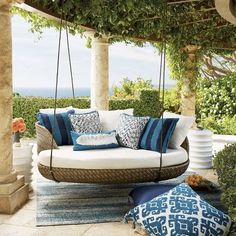 an outdoor swing chair with blue and white pillows