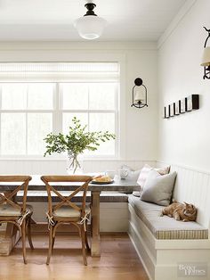 a dining room table with chairs and a bench in front of the window next to it