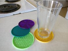 three coasters sitting on top of a counter next to a cup and burner