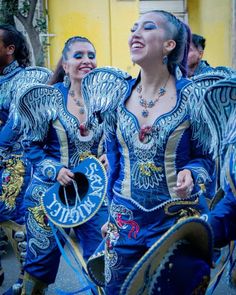 three women in blue and gold costumes are walking down the street with their arms around each other