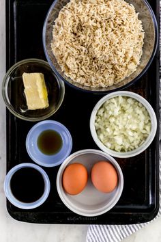 ingredients for rice and eggs laid out on a black tray, ready to be cooked