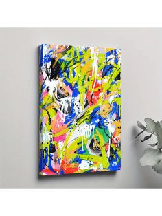 an abstract painting on the wall next to a plant