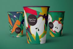 three paper cups with designs on them sitting next to each other in front of a green background