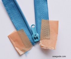 two zippers are open on a white surface, one has an adhesive tape and the other is closed