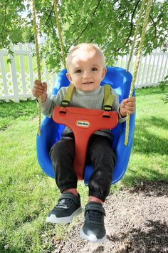 a little boy sitting in a blue swing