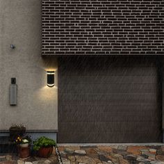 a garage door with lights on it in the rain next to a planter and potted plants