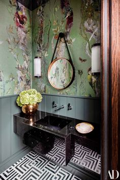 a bathroom with green walls and floral wallpaper on the walls, along with a black marble countertop