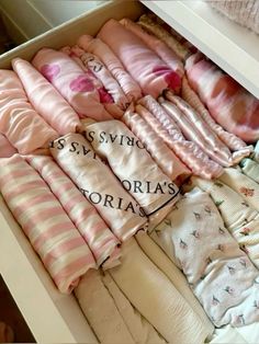 an open drawer filled with lots of pink and white baby swaddles on top of each other