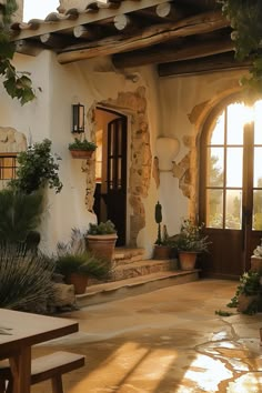 the sun shines through an arched doorway into a house with potted plants on either side