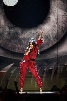 the woman is performing on stage with her arms in the air