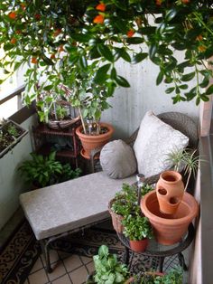 some potted plants are sitting on a small patio table next to an outdoor bench