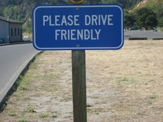 a blue sign sitting on the side of a road next to a grass covered field