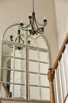 a chandelier hanging from the side of a wooden banister in front of a mirror