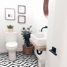 a white toilet sitting next to a sink in a bathroom under pictures on the wall