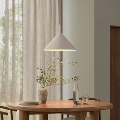 a dining room table with two vases on it and a lamp hanging from the ceiling