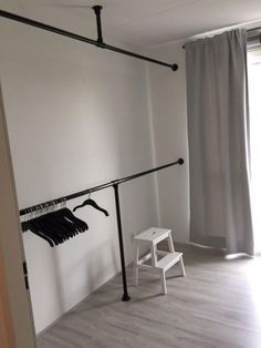 an empty room with clothes hanging on the rail and a chair in front of it