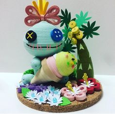 an odd looking stuffed animal sitting on top of a wooden base next to flowers and plants