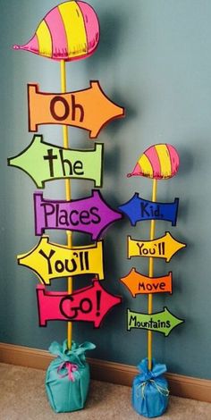 two colorful wooden signs on top of each other in front of a blue wall with the words oh the places you'll go