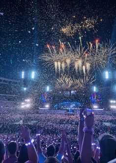 a large crowd at a concert with fireworks and confetti