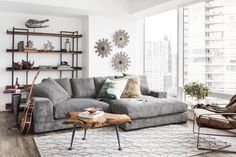 a living room filled with furniture and a large window covered in lots of natural light