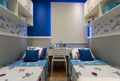 two twin beds in a room with blue walls and white shelvings on the wall