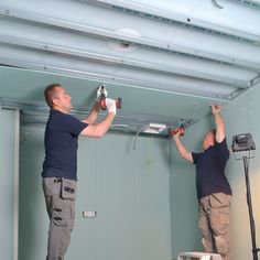 two men working on the ceiling in a room