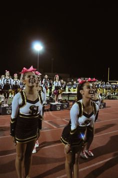 two cheerleaders in black and white uniforms on a track with lights behind them