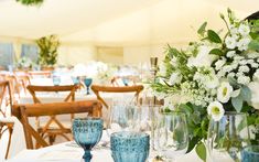 a table set up with blue vases and white flowers on it for a wedding reception