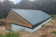 a small building with a metal roof in the woods