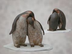 two small figurines of penguins sitting on top of each other, facing opposite directions