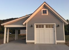 a garage with an attached carport in front of it and two doors on the side